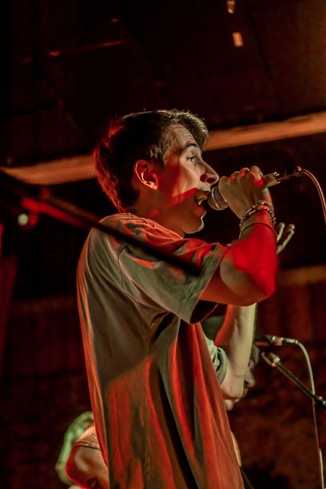 Danny singing into a microphone on a dark stage
