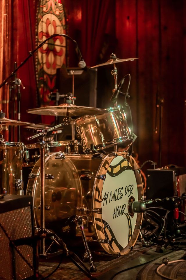 A drum set on stage in front of a red curtain