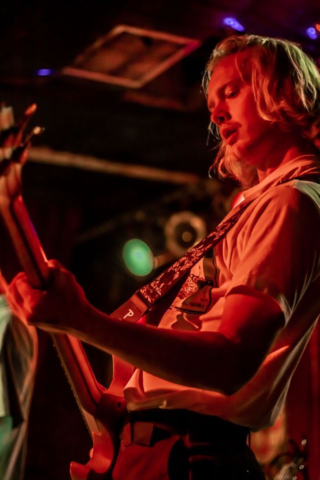 A band member playing guitar in a dark room