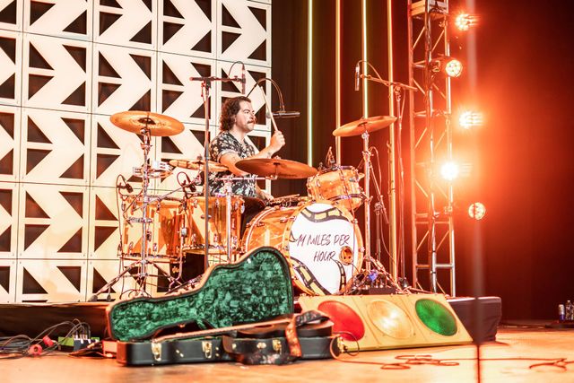 Drummer performing with guitar in the foreground