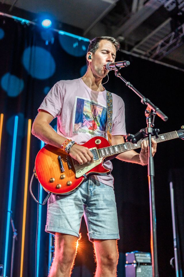 Guitarist singing into a microphone on stage
