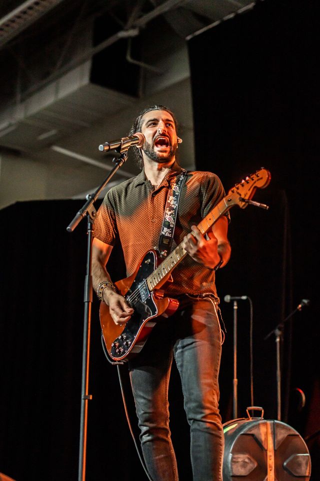 Singing and playing guitar under stage lights