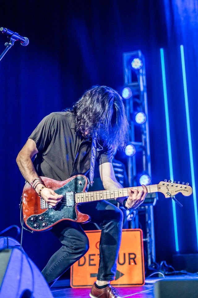Guitarist performing beside a detour sign