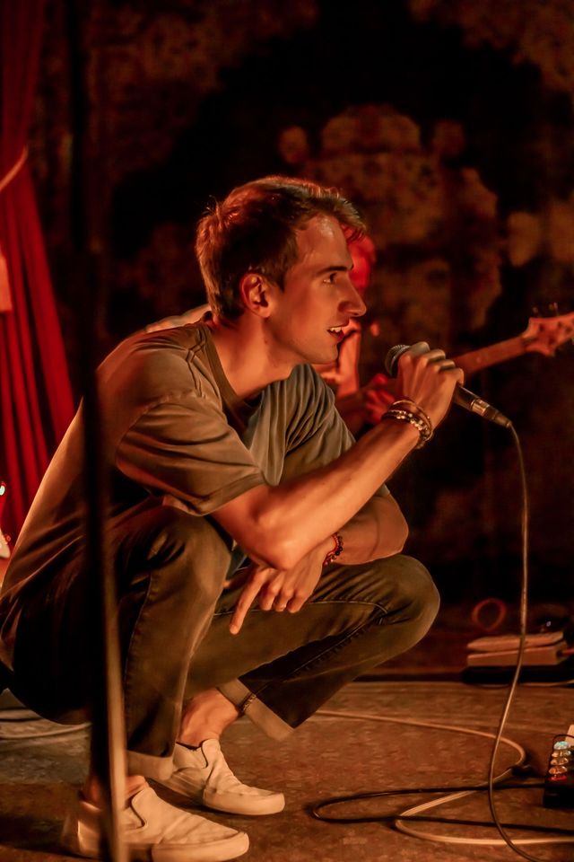 Vocalist kneeling while singing on stage