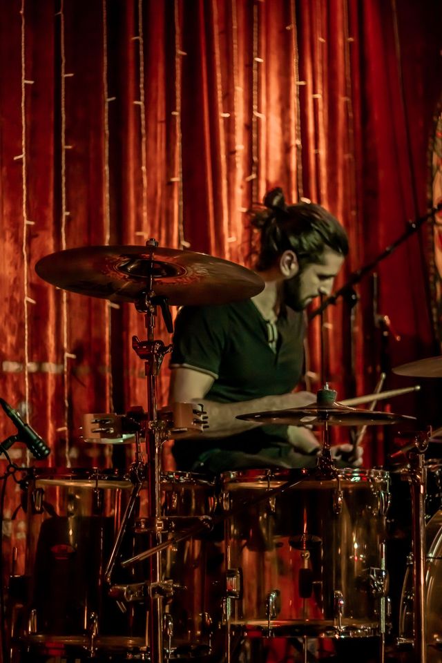 Drummer performing in front of a red curtain