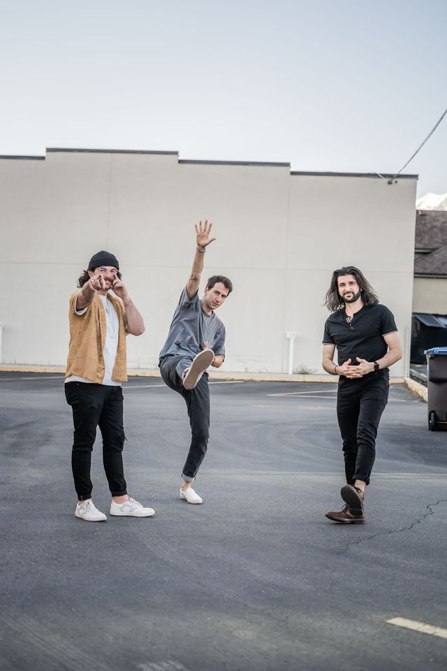 Three band members standing in a parking lot